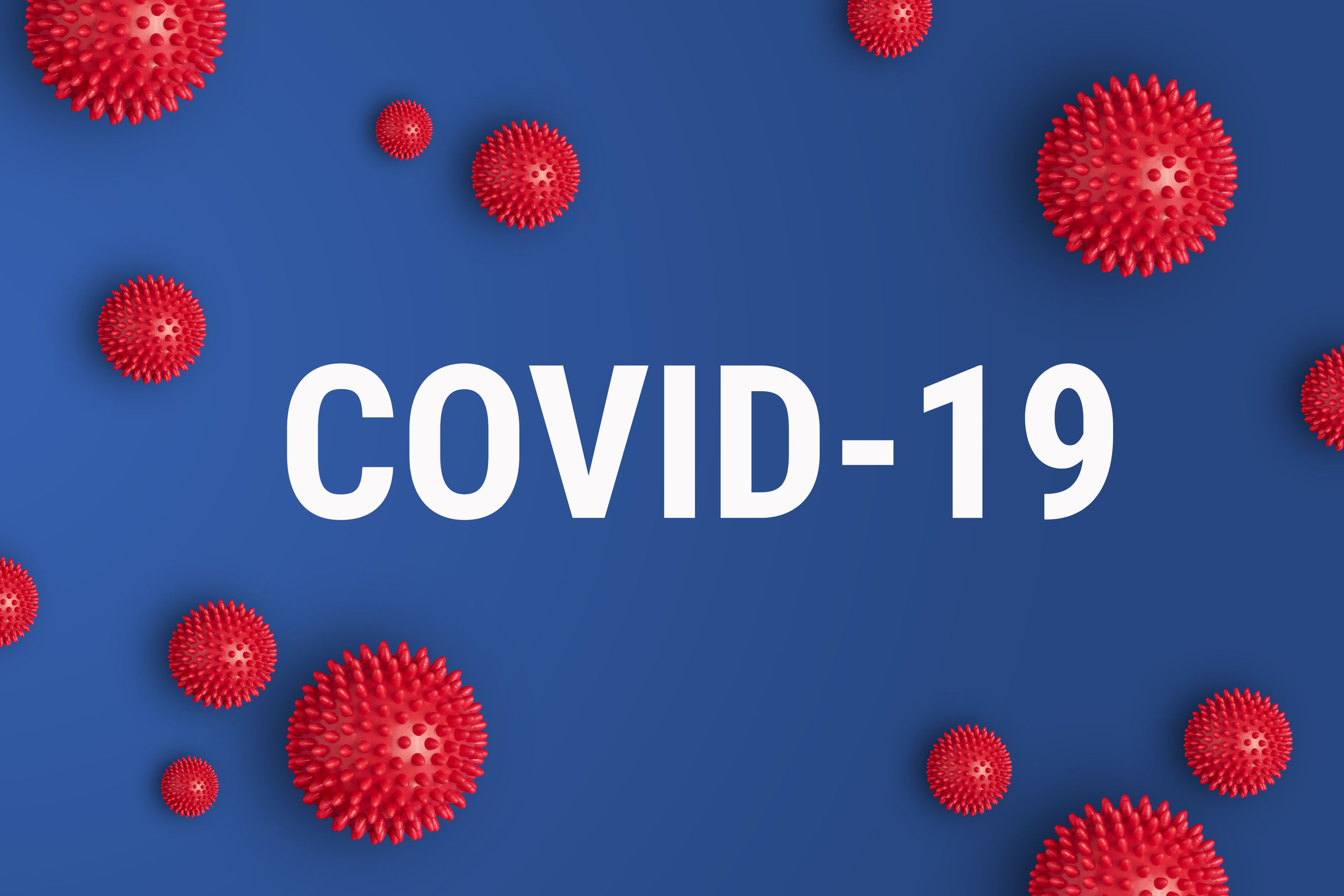 Inscription COVID-19 on blue background with red strain model of coronavirus